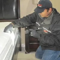 Bed bug inspection technician checking a mattress and bed frame for signs of infestation in Scottsdale, AZ