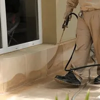 General pest control technician spraying exterior perimeter around a home in Scottsdale, AZ
