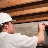 Termite inspection technician checking a basement wall and framing for termite activity in Scottsdale, AZ